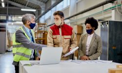 Woodworking company managers communicating with male worker at production facility.